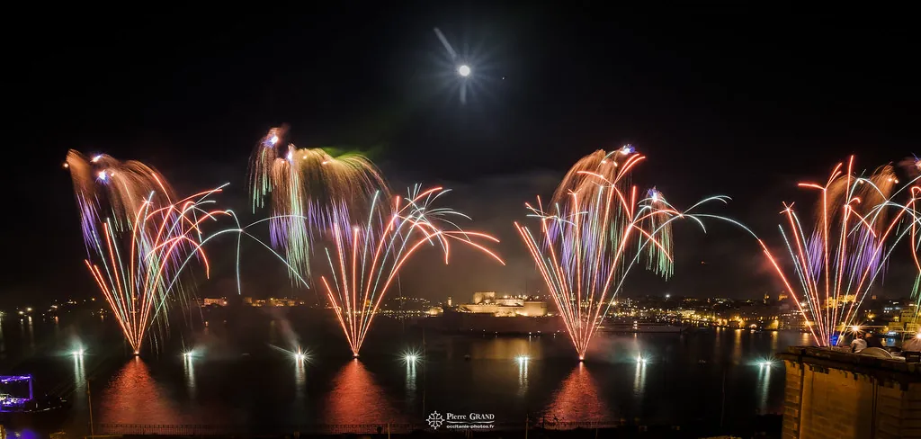 Palmiers orangés et leurs reflets sur l'eau, feu d'artifice du Grand Harbour, La Valette (Malte)